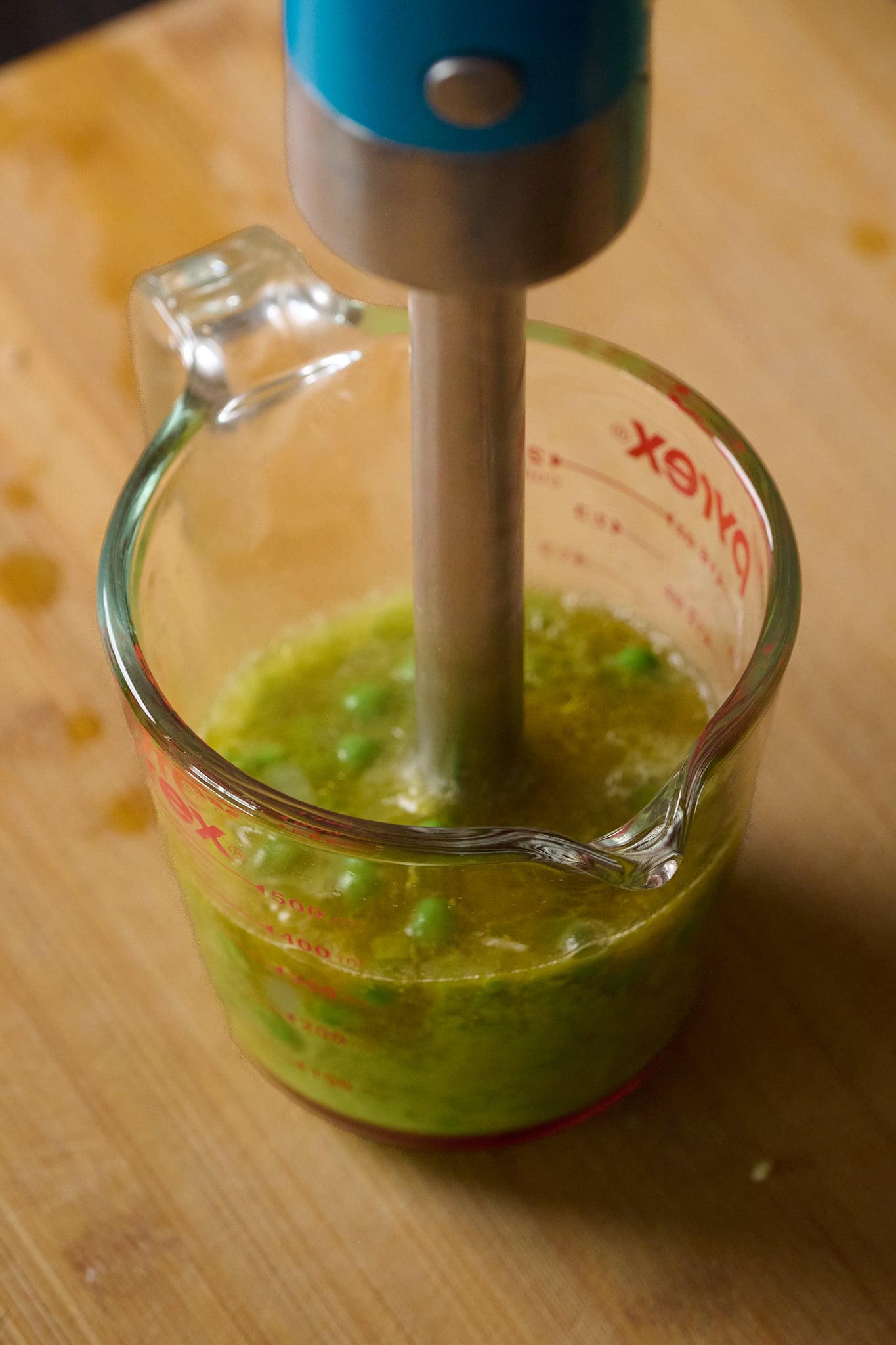 Glass jar has immersion blender going into it.