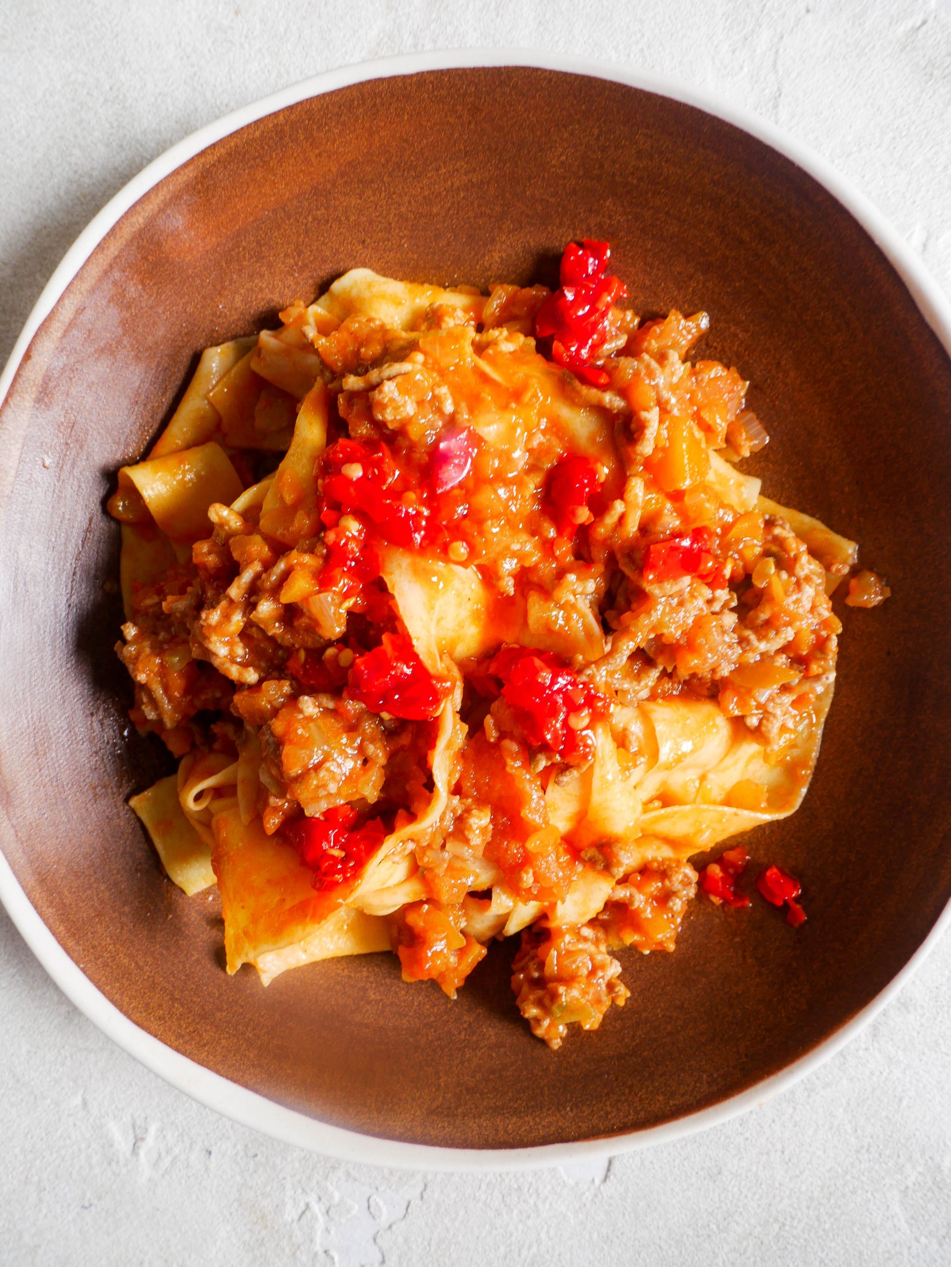 A large pot of simmering Ragu Bolognese sauce on a stovetop.