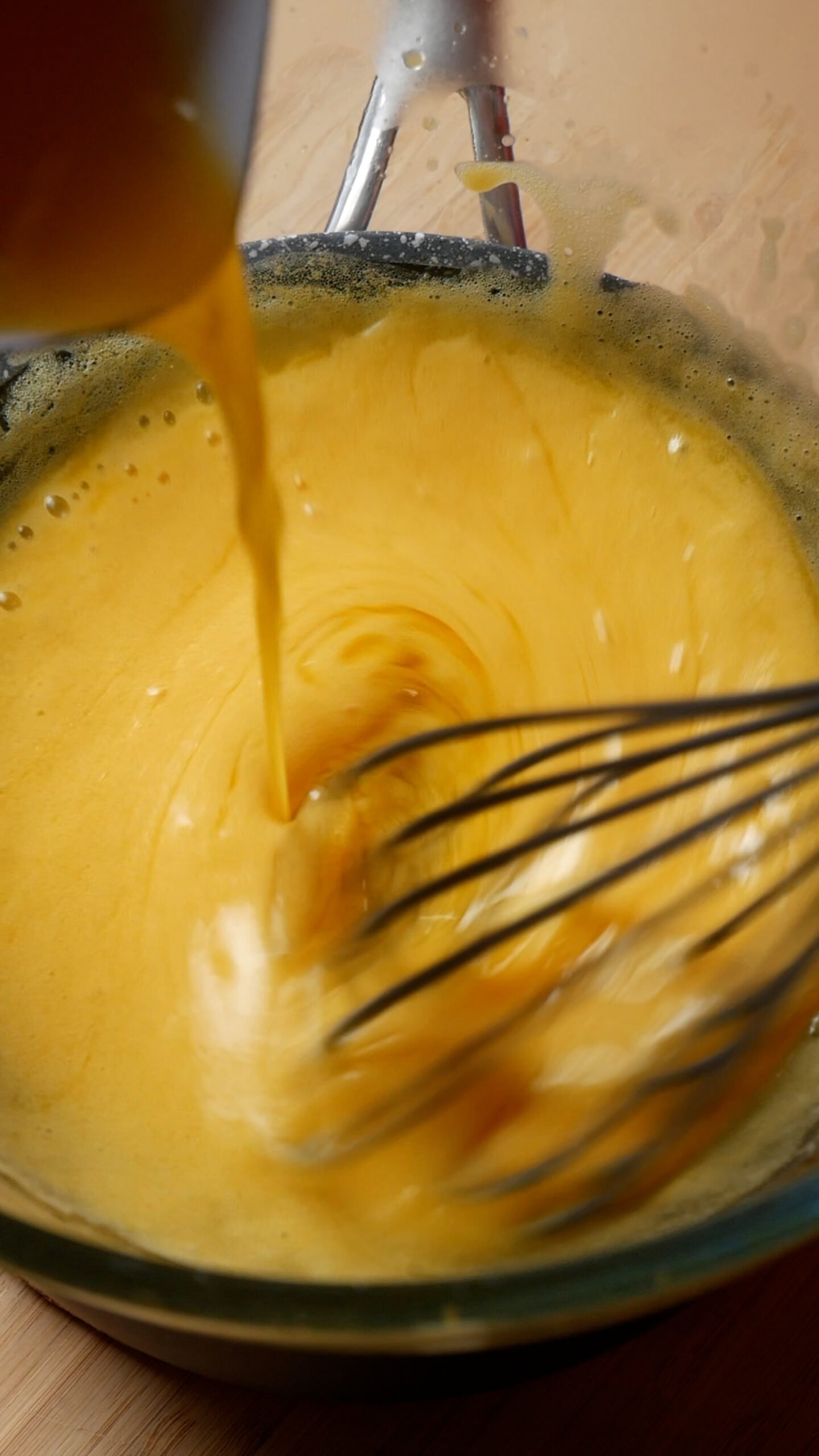 Hollandaise sauce is being made. You can see whisk and butter being streamed into glass bowl. 