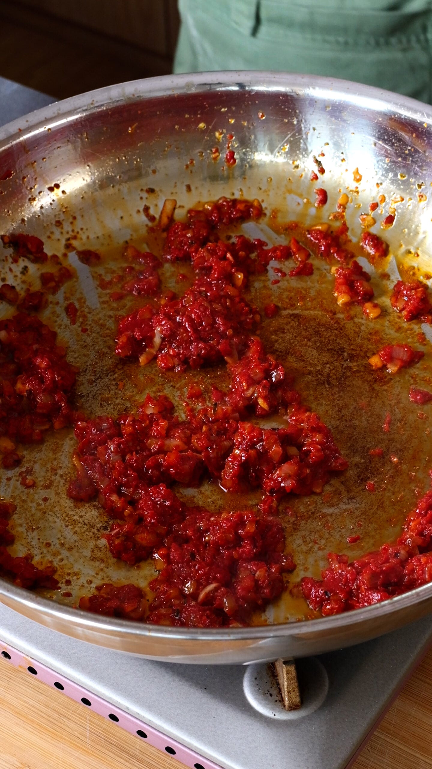 Stainless steel pan has onion and tomato paste in it.