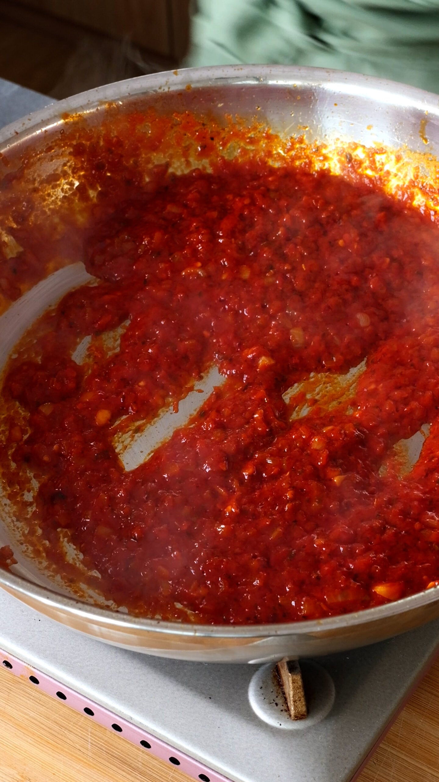 Stainless steel pan is shown with tomato paste, onion and vodka.