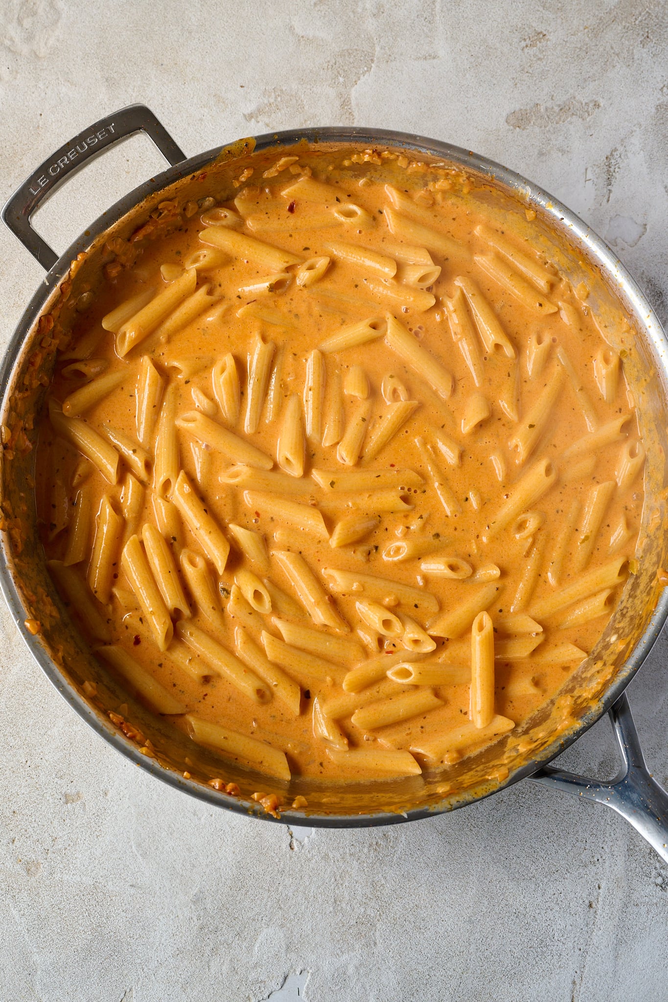 Stainless steel pan is shown with pasta and vodka sauce.