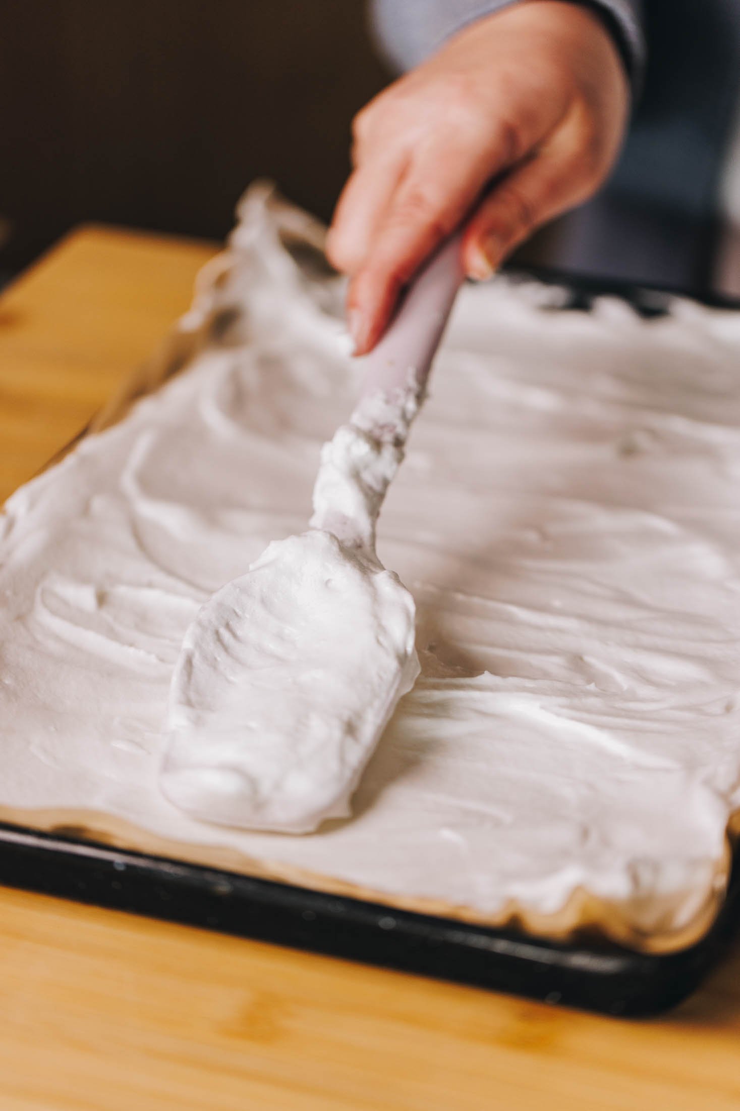 Meringue is being spread onto prelined baking tray.