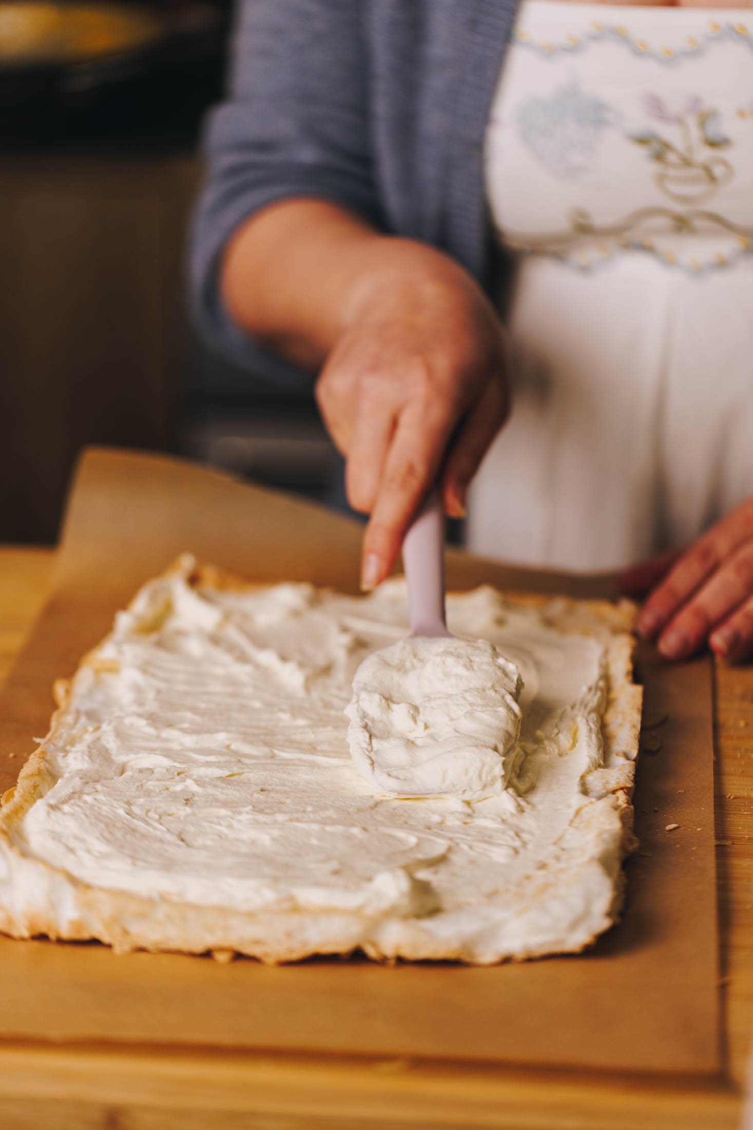 Cooked meringue has been remove from baking tray and is being layered with whipped cream.