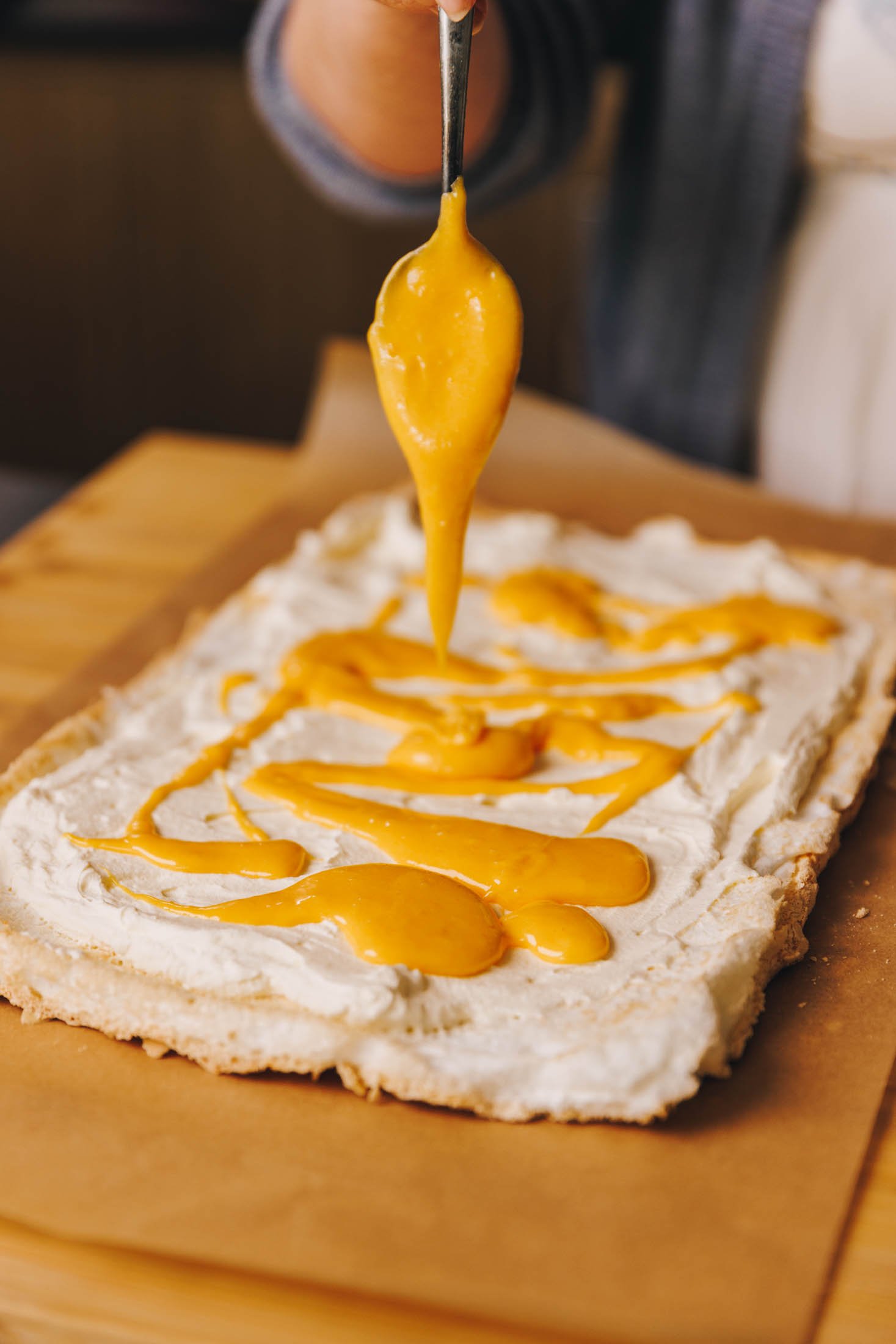 Lemon curd is being drizzled onto meringue