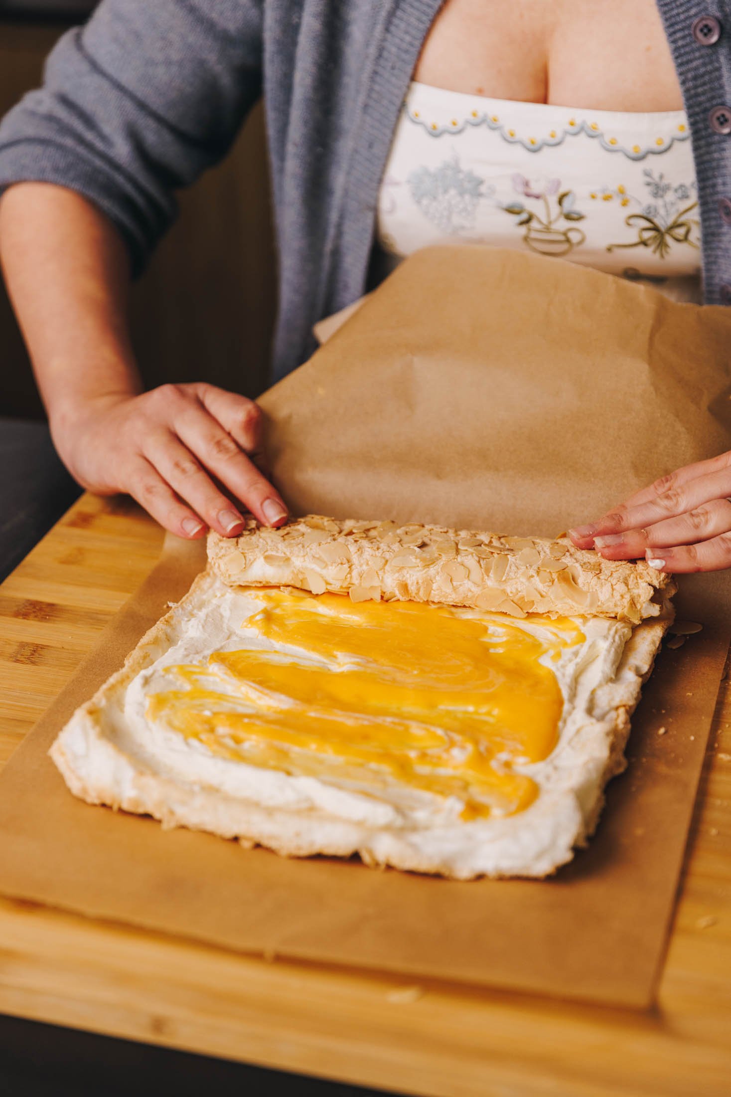 You can see baking paper and two hands rolling roulade.