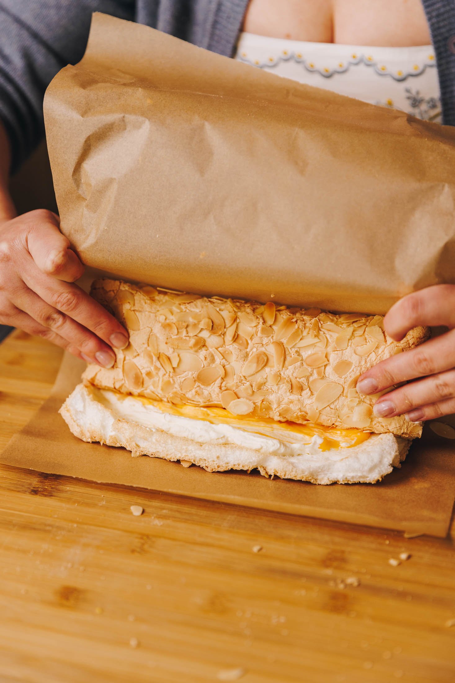 You can see baking paper and two hands rolling roulade.