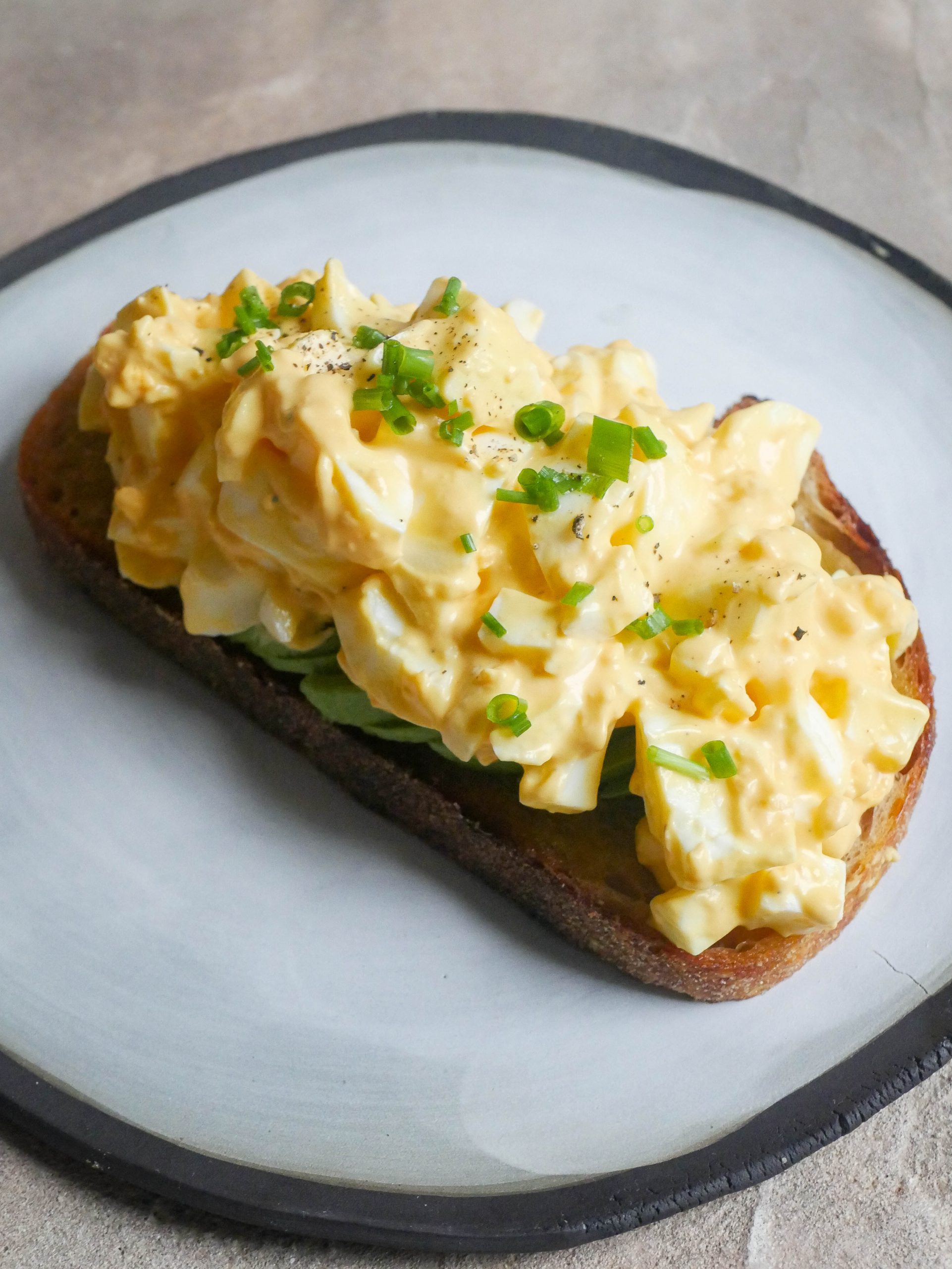 egg salad on piece of toast sitting on plate
