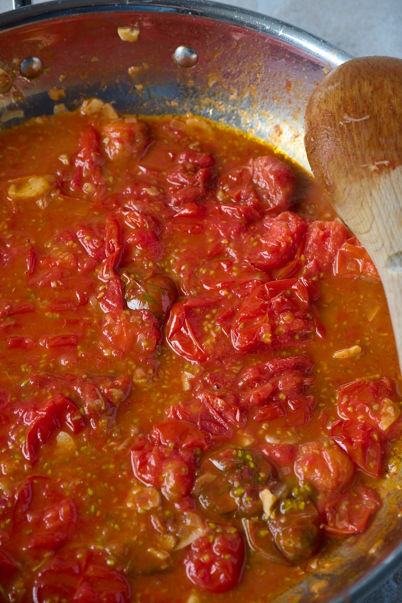 Cherry tomatoes have been cooked and are in a large frypan