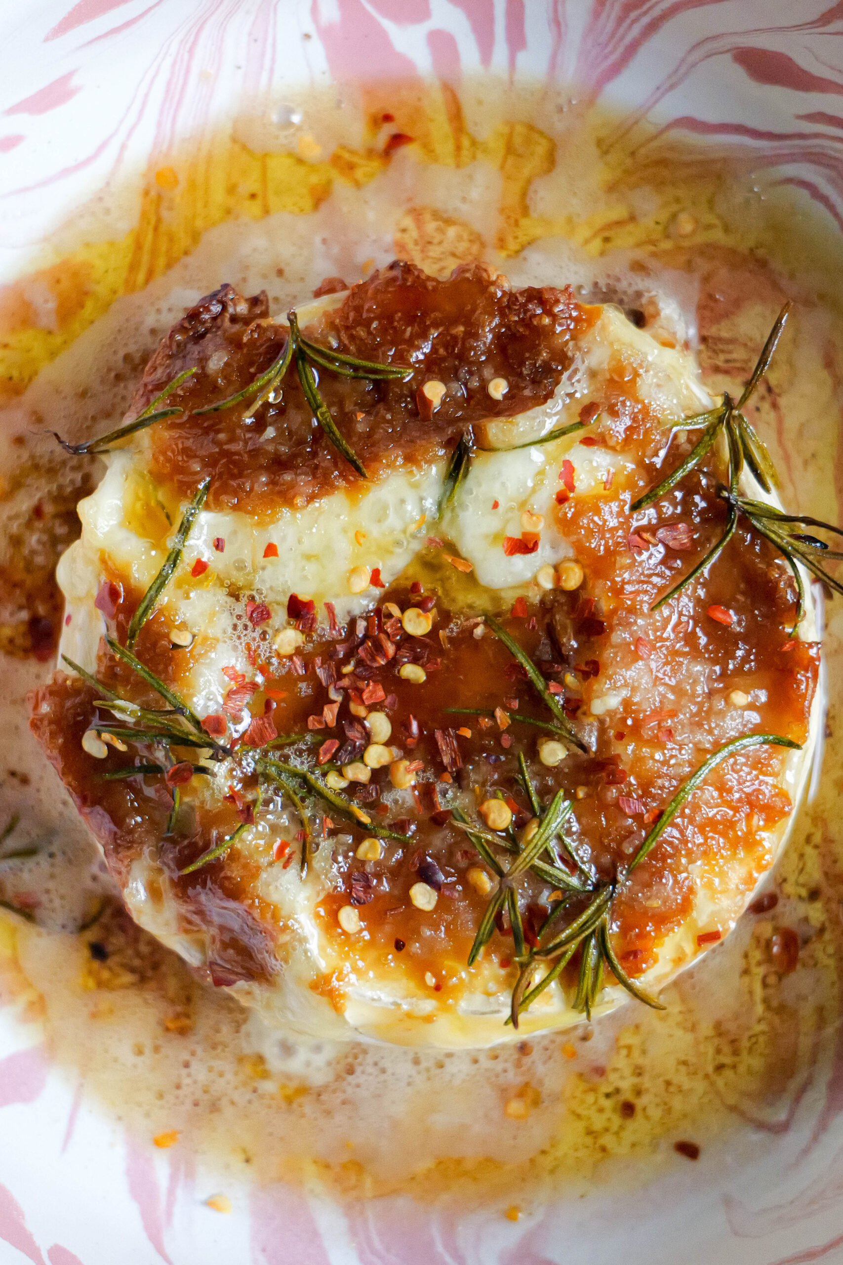 Baked brie with roasted garlic butter sits in pink and white tray