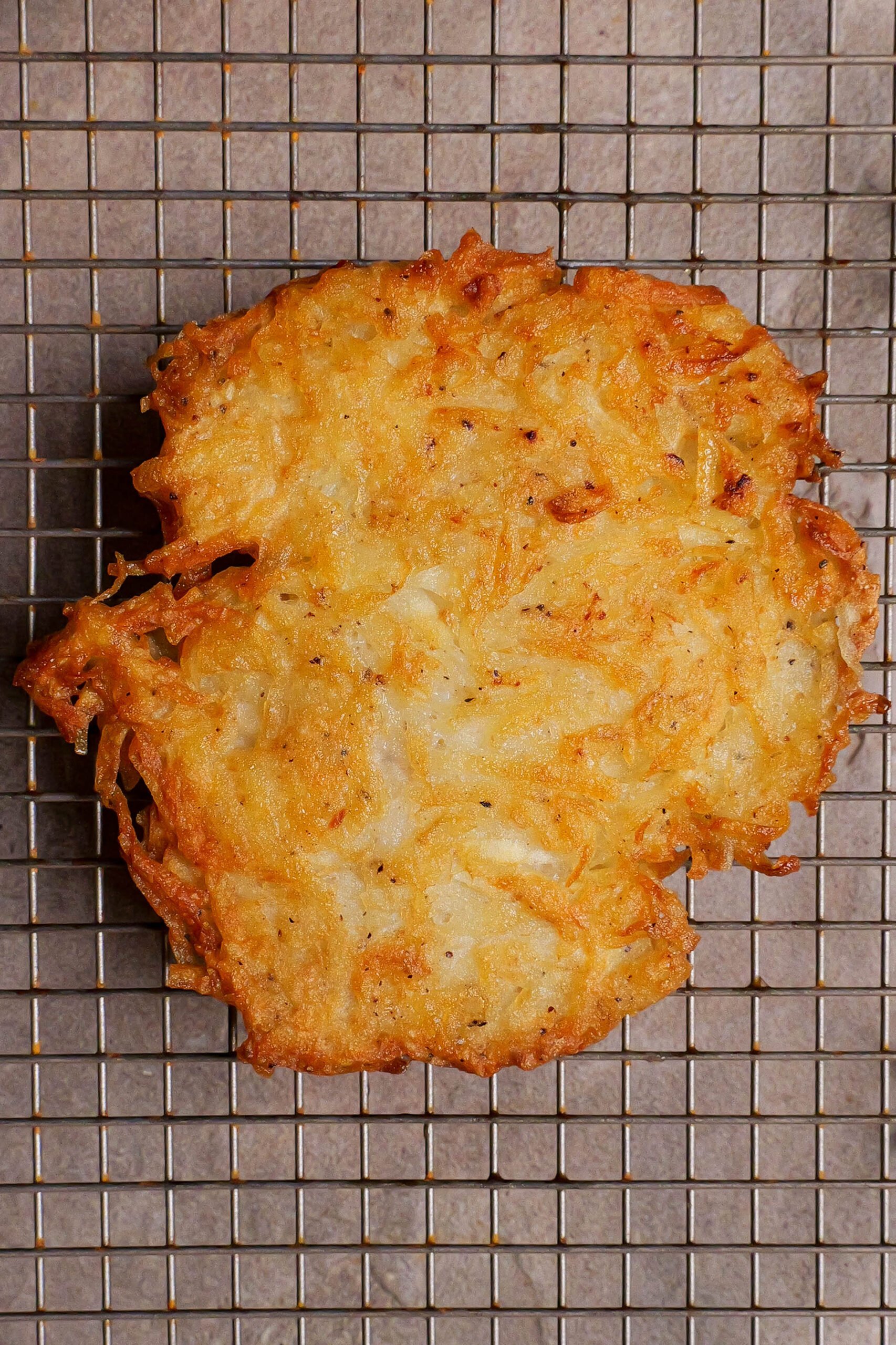 Potato rosti sit on a circular wire cooling rack. 
