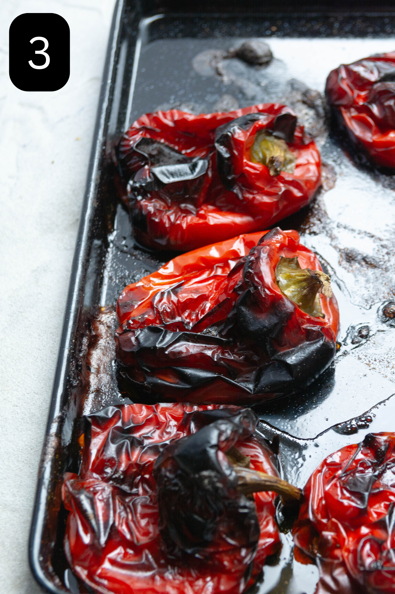 Charred red peppers lay on a baking tray