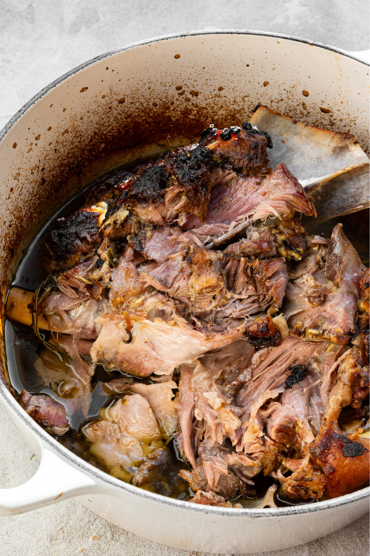 Lamb that has been shredded in large white pot. 