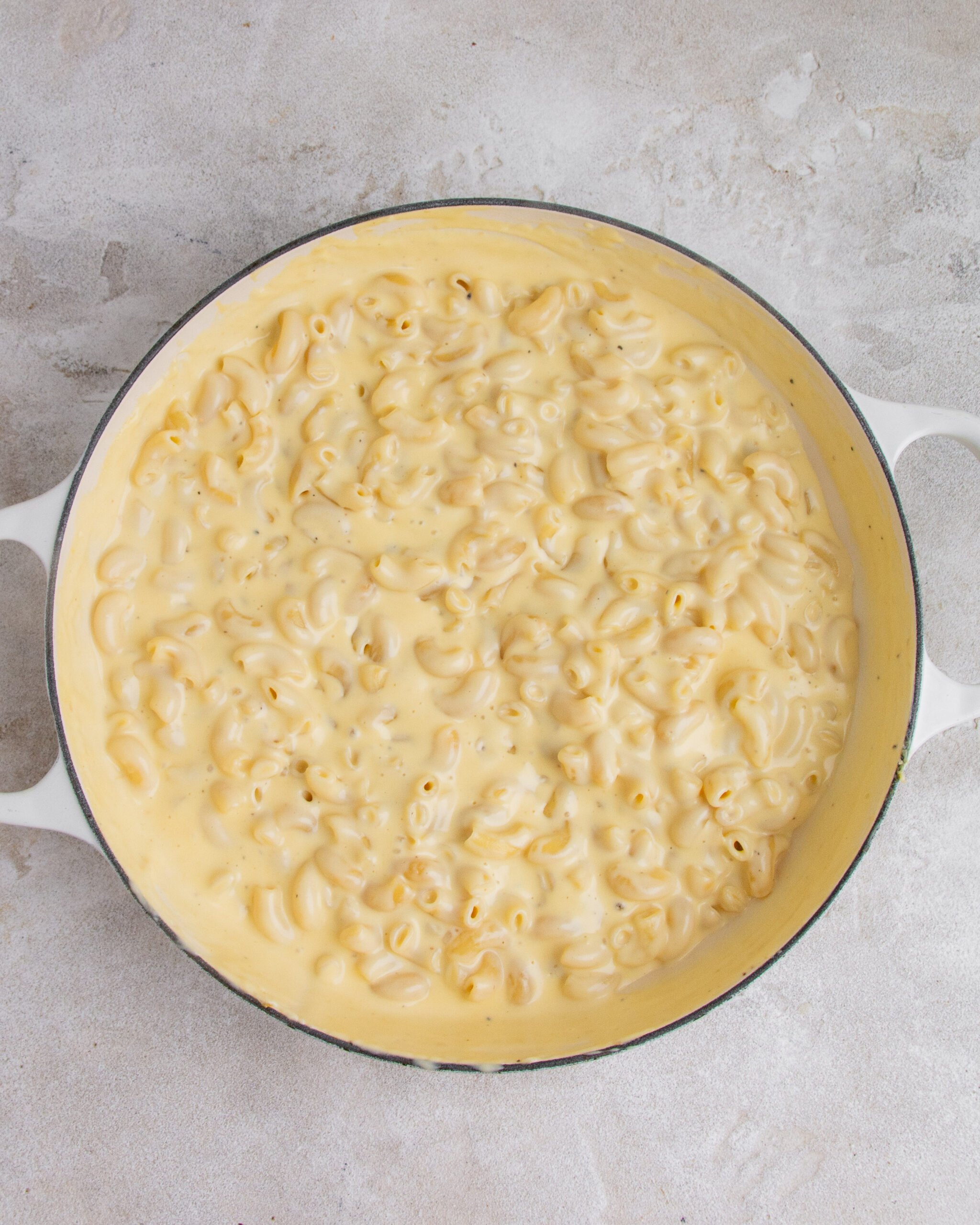 Baked mac and cheese with garlic confit is in large white baking tray and has not been baked. 