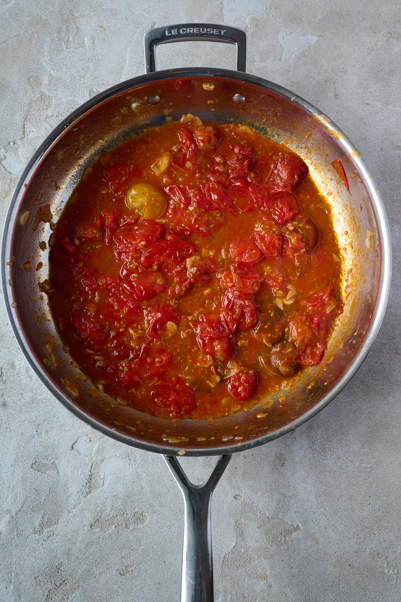 Blistered cherry tomatoes are in stainless steel pan