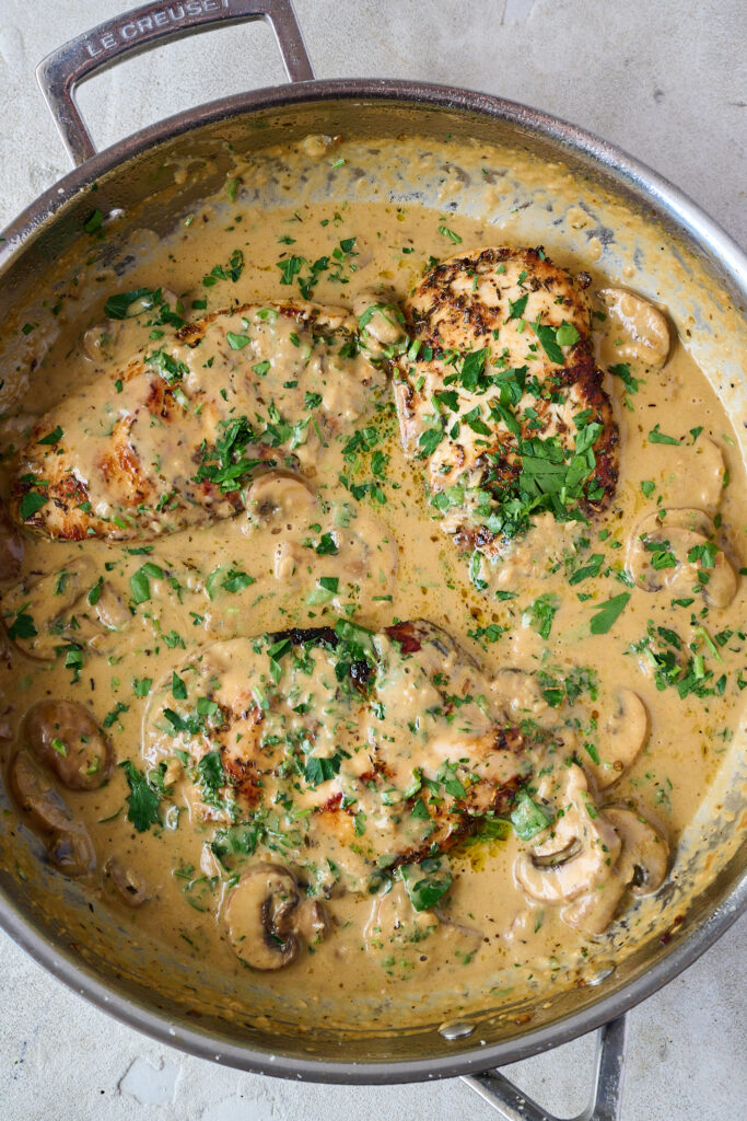 Chicken in pan with creamy mushroom sauce and finished with sprinkling of fresh parsley