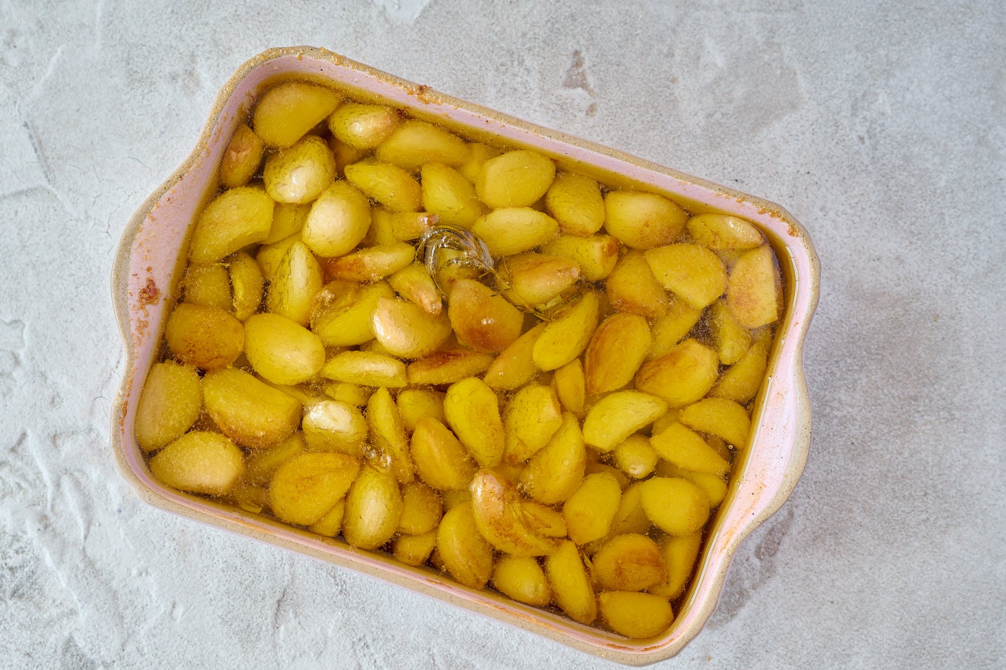 Garlic are golden and baked and are in pink baking dish