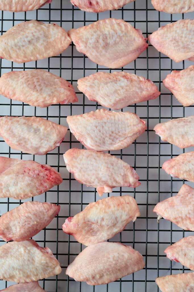 Raw uncooked chicken wings lay on wire rack