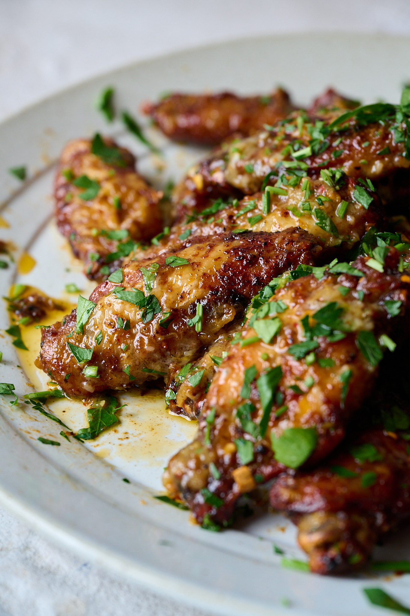 Oven baked crispy wings with lemon and garlic sauce in a bowl and topped with freshly chopped parsley. 