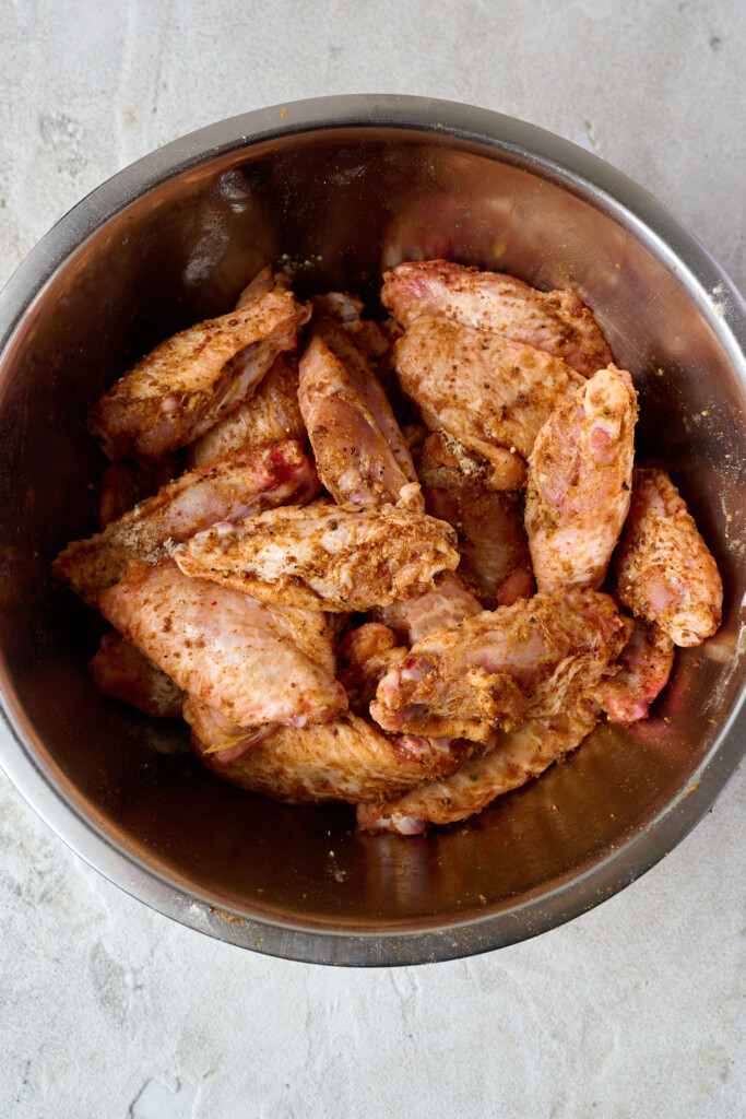 Raw uncooked wings in bowl that have been coated in spices and baking powder