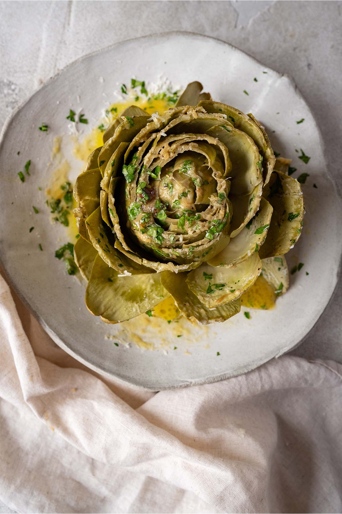 large artichoke with garlic butter on a plate.