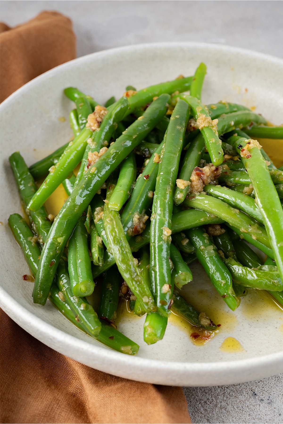 garlicky green beans on a plate with a brown napkin.