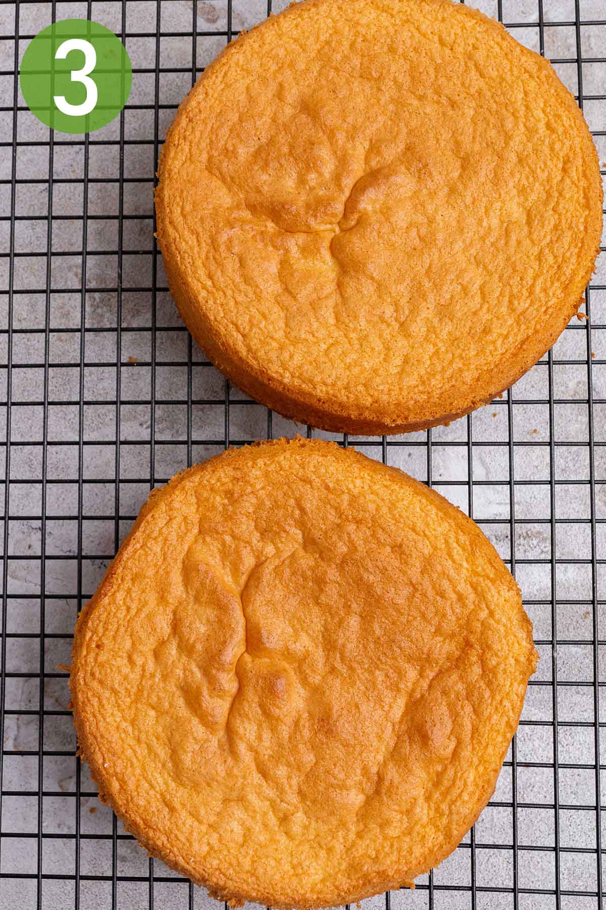 two baked sponge cakes on a wire rack.