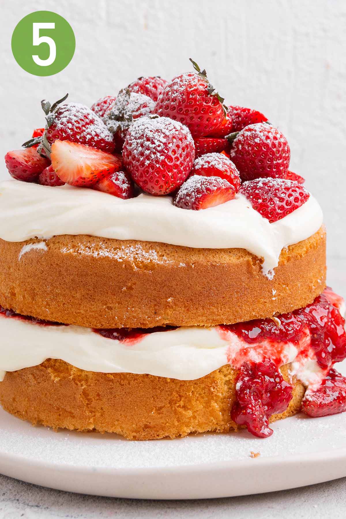 two layer sponge cake layered with whipped cream and strawberries.