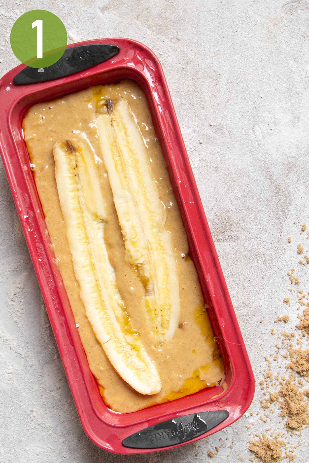 unbaked banana bread in a red loaf pan.
