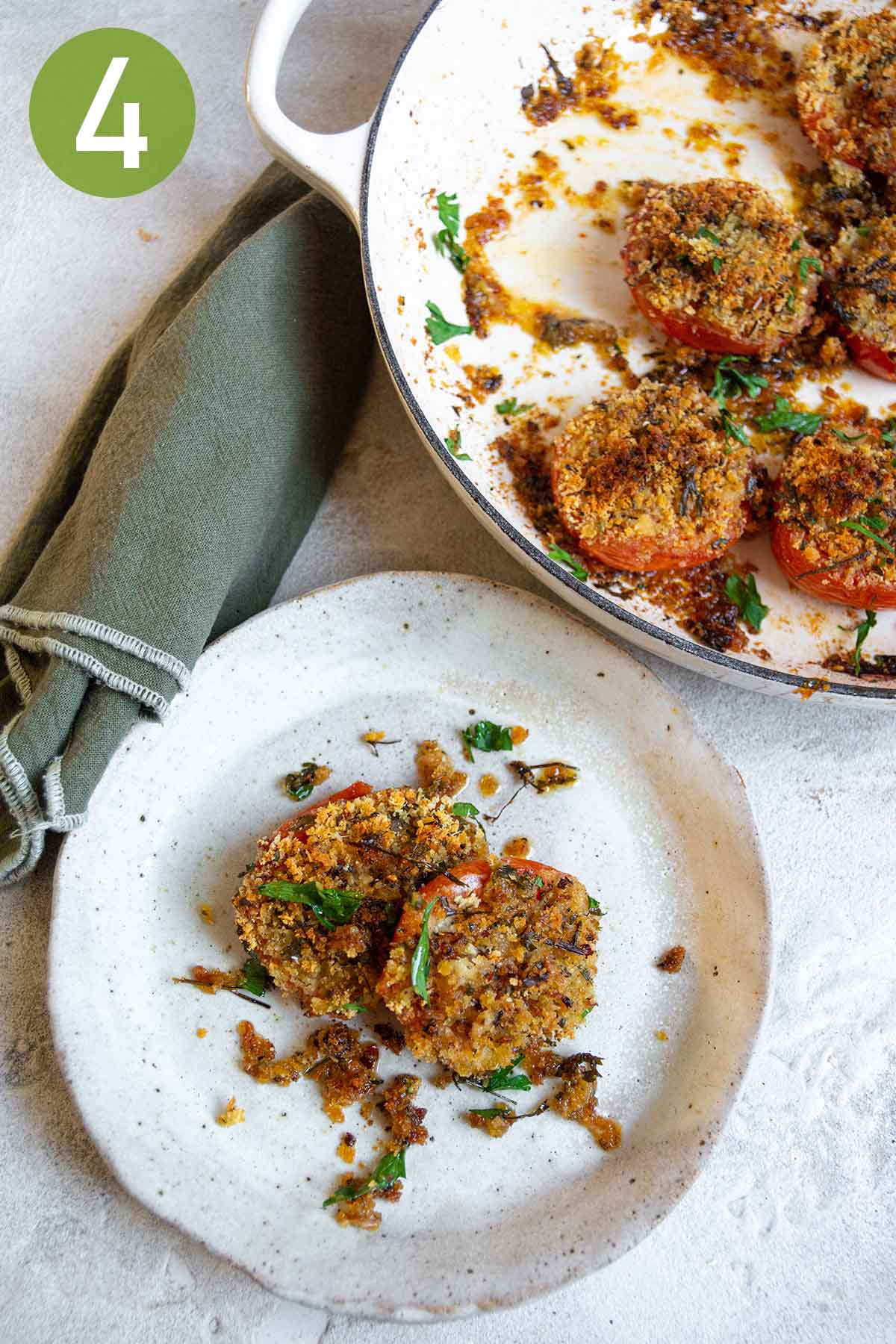 two breadcrumb stuffed tomatoes on a white plate.