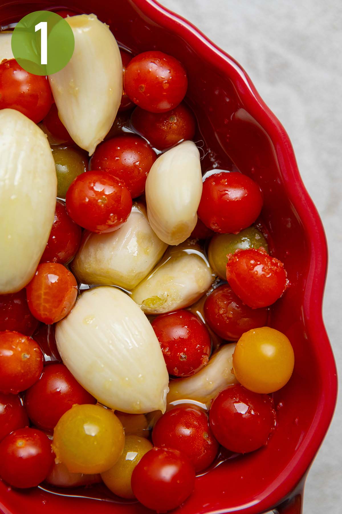 tomatoes, garlic, and olive oil in a red pot.