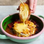 spreading the melted brie on a toasted baguette slice.