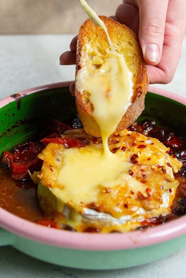 spreading the melted brie on a toasted baguette slice.