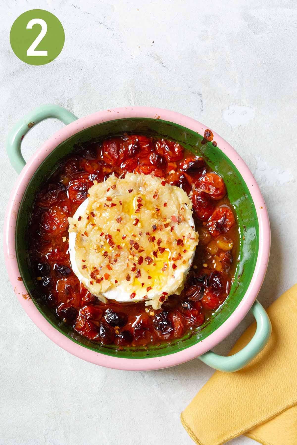 topping brie with garlic and chilli flakes with tomatoes.