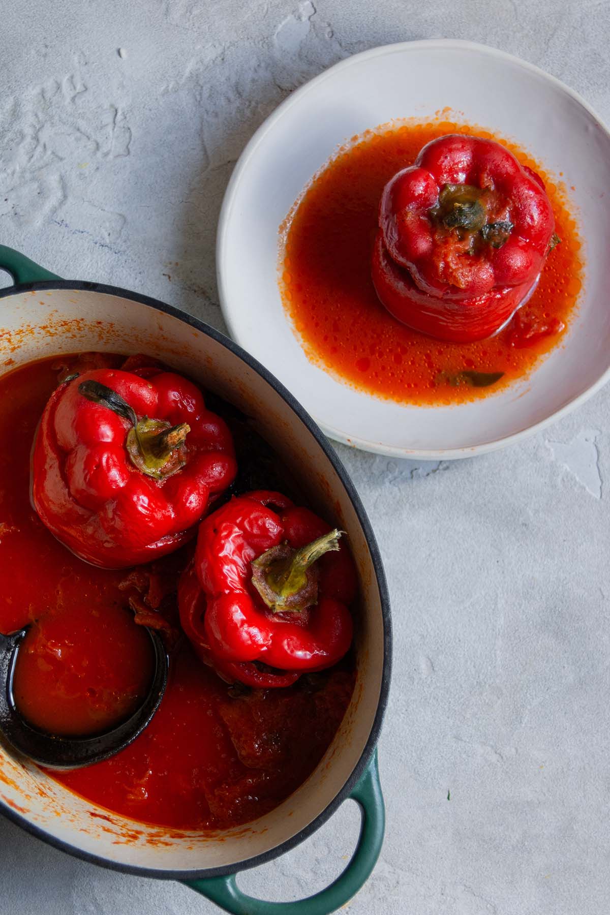 stuffed red bell peppers in a pot and on a plate.