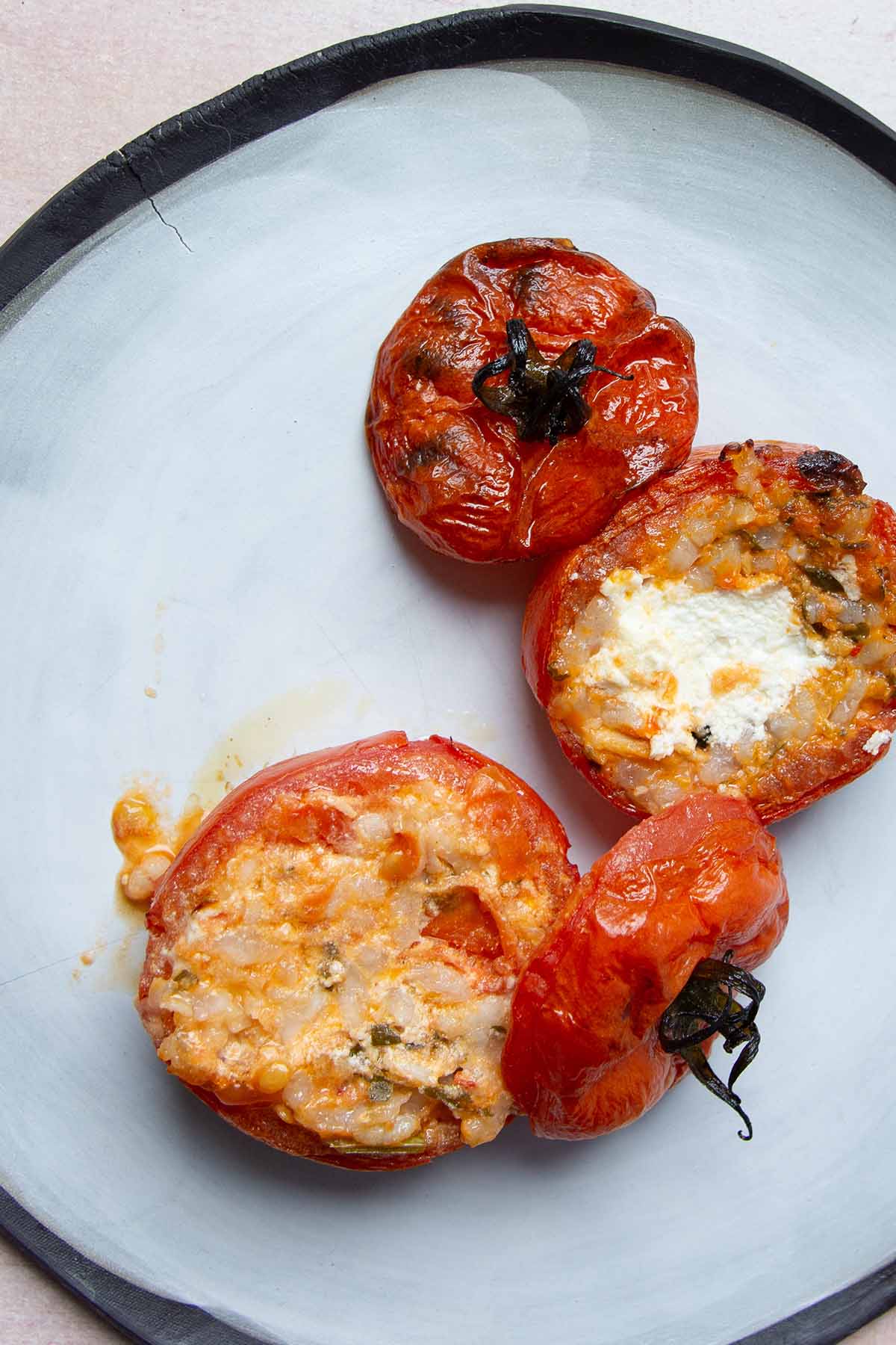 two stuffed tomatoes on a white plate.