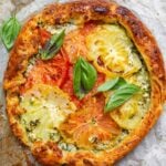 summer tomato tart with fresh basil on parchment paper.