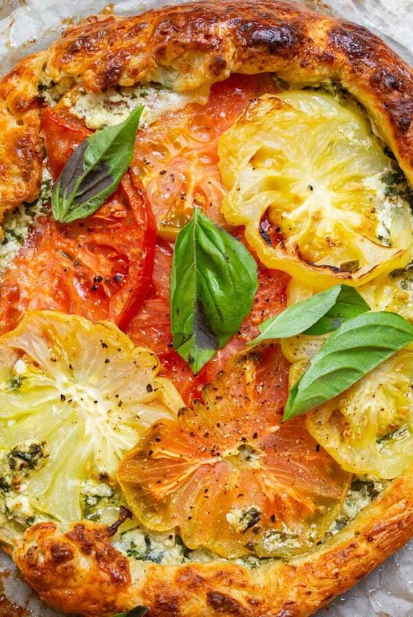 summer tomato tart with fresh basil on parchment paper.