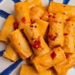 blue and white striped plate of tomato garlic confit pasta.