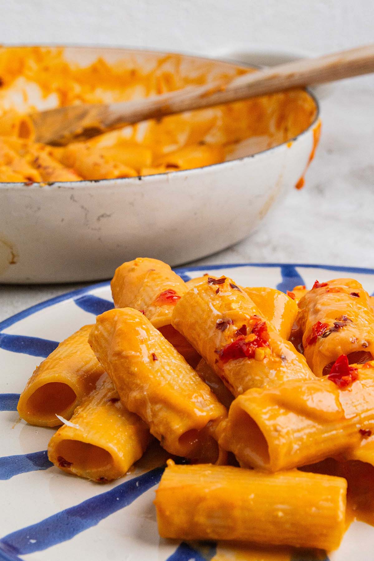 serving tomato garlic confit pasta with a wooden spoon.