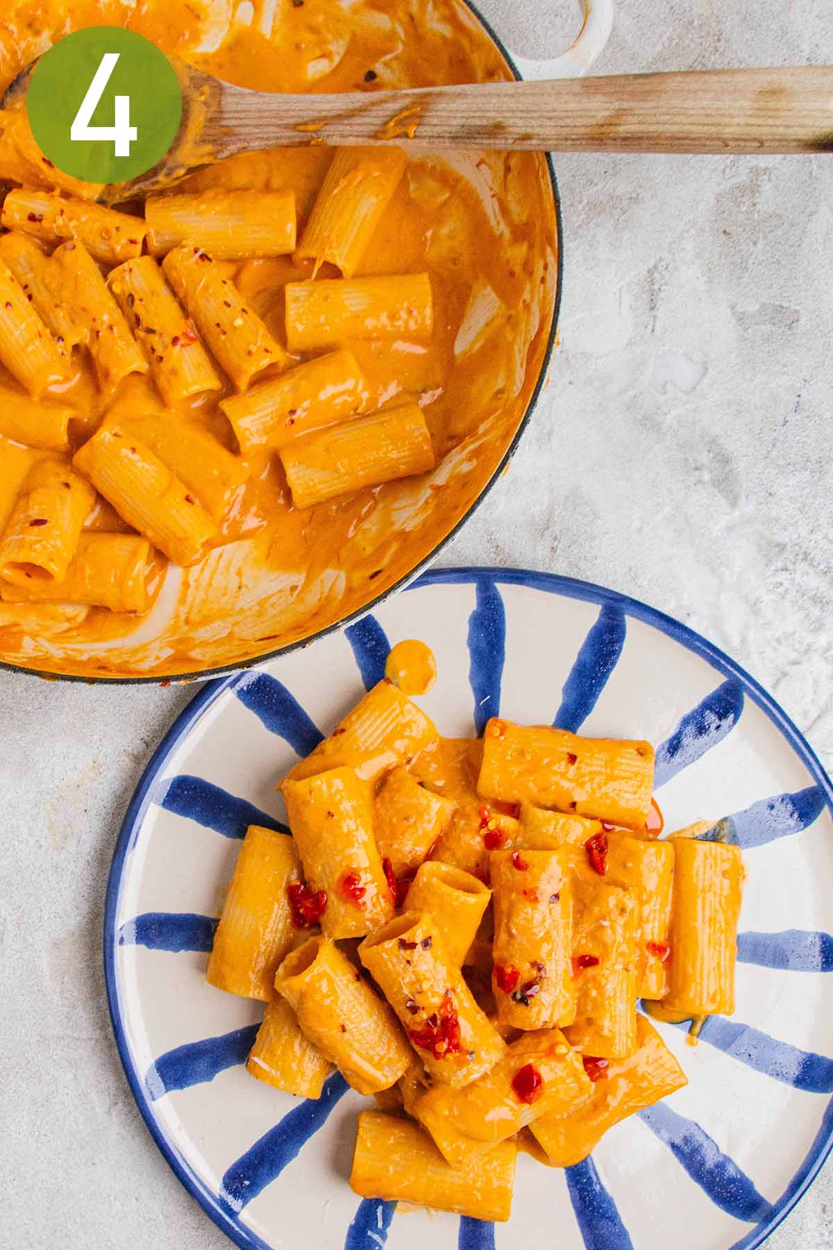 serving tomato garlic confit pasta with a wooden spoon.
