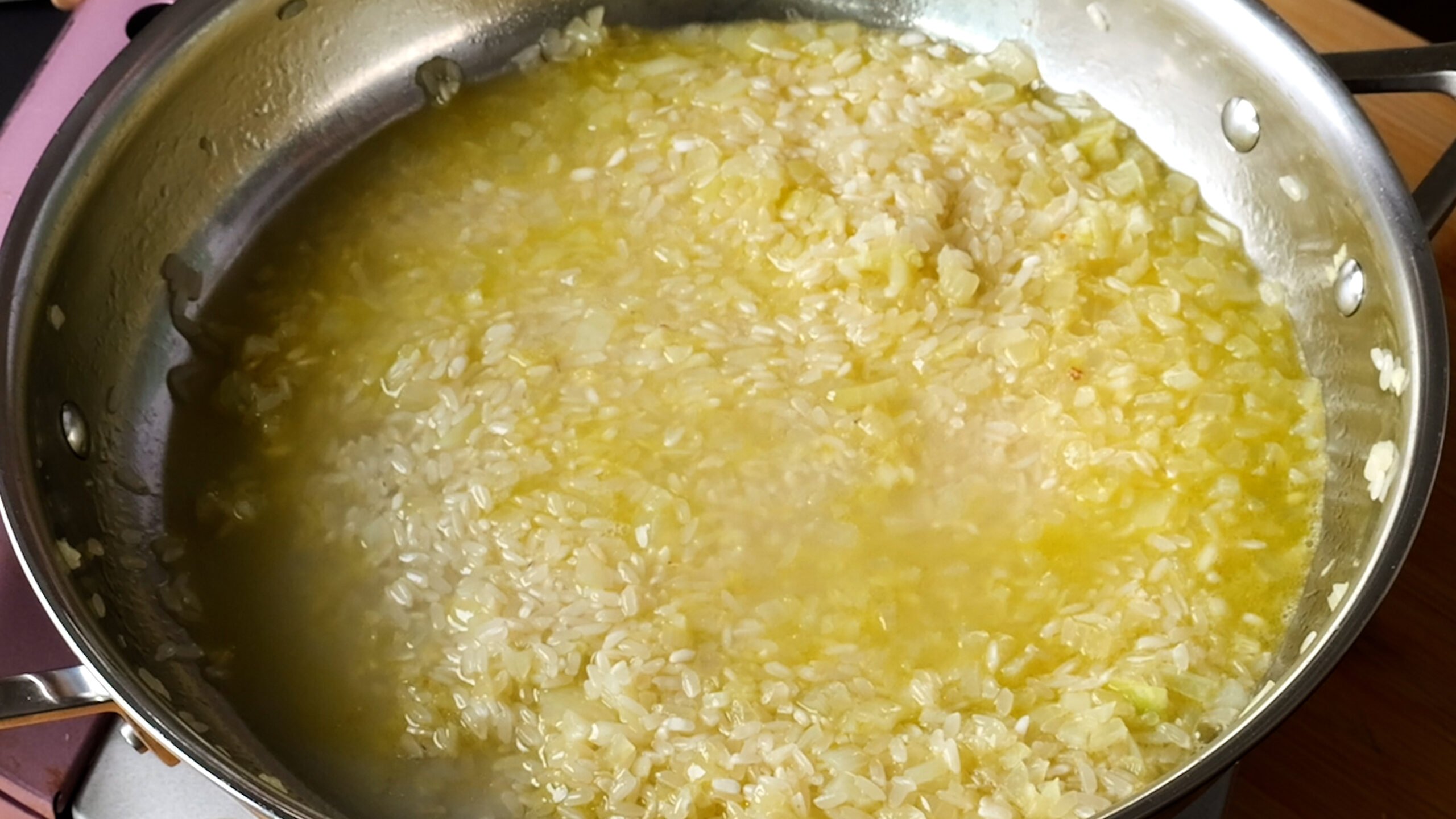 Image of stainless steel pan with rice and stock added. 