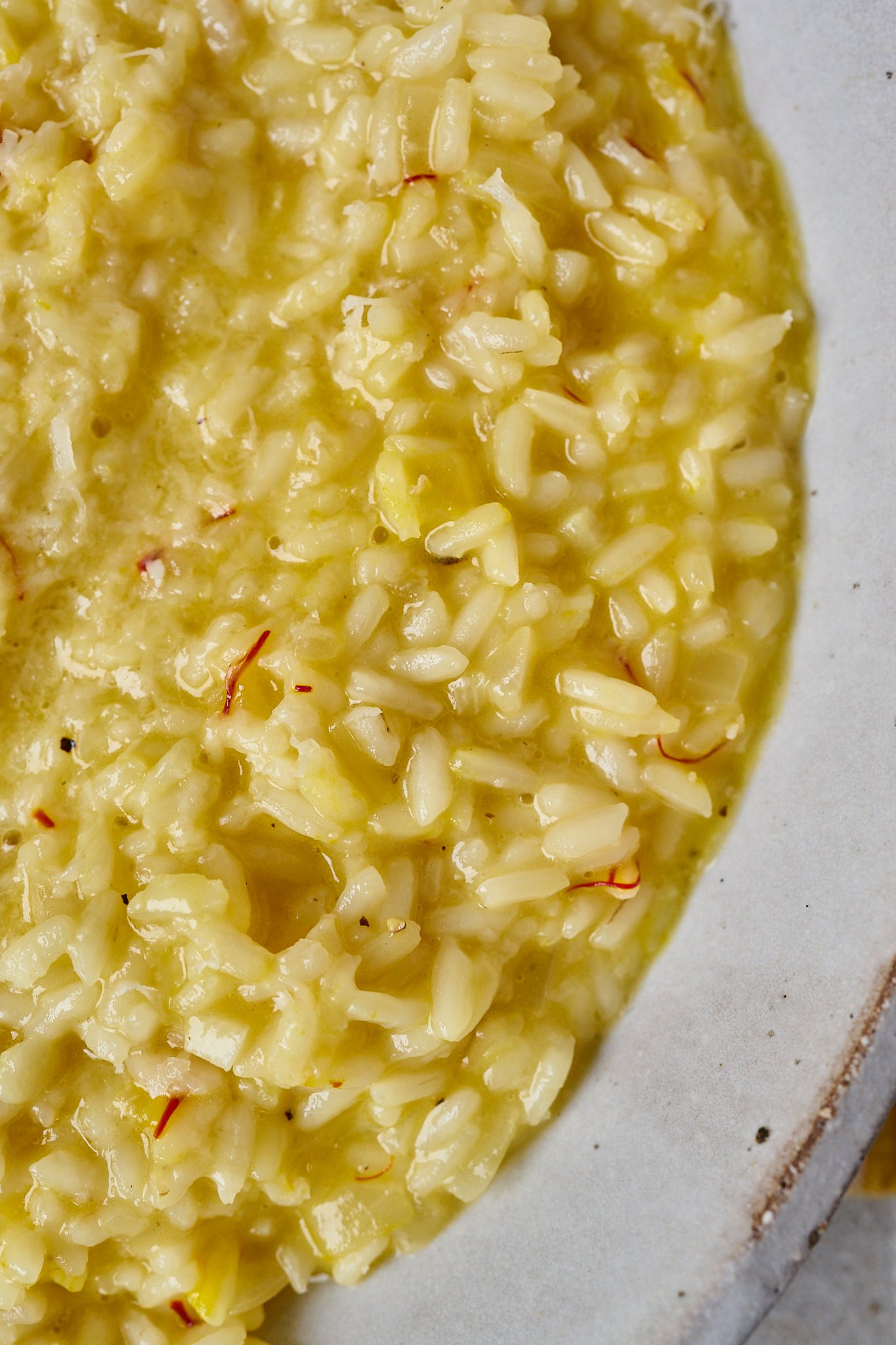 Close up image of risotto alla milanese in white bowl. 