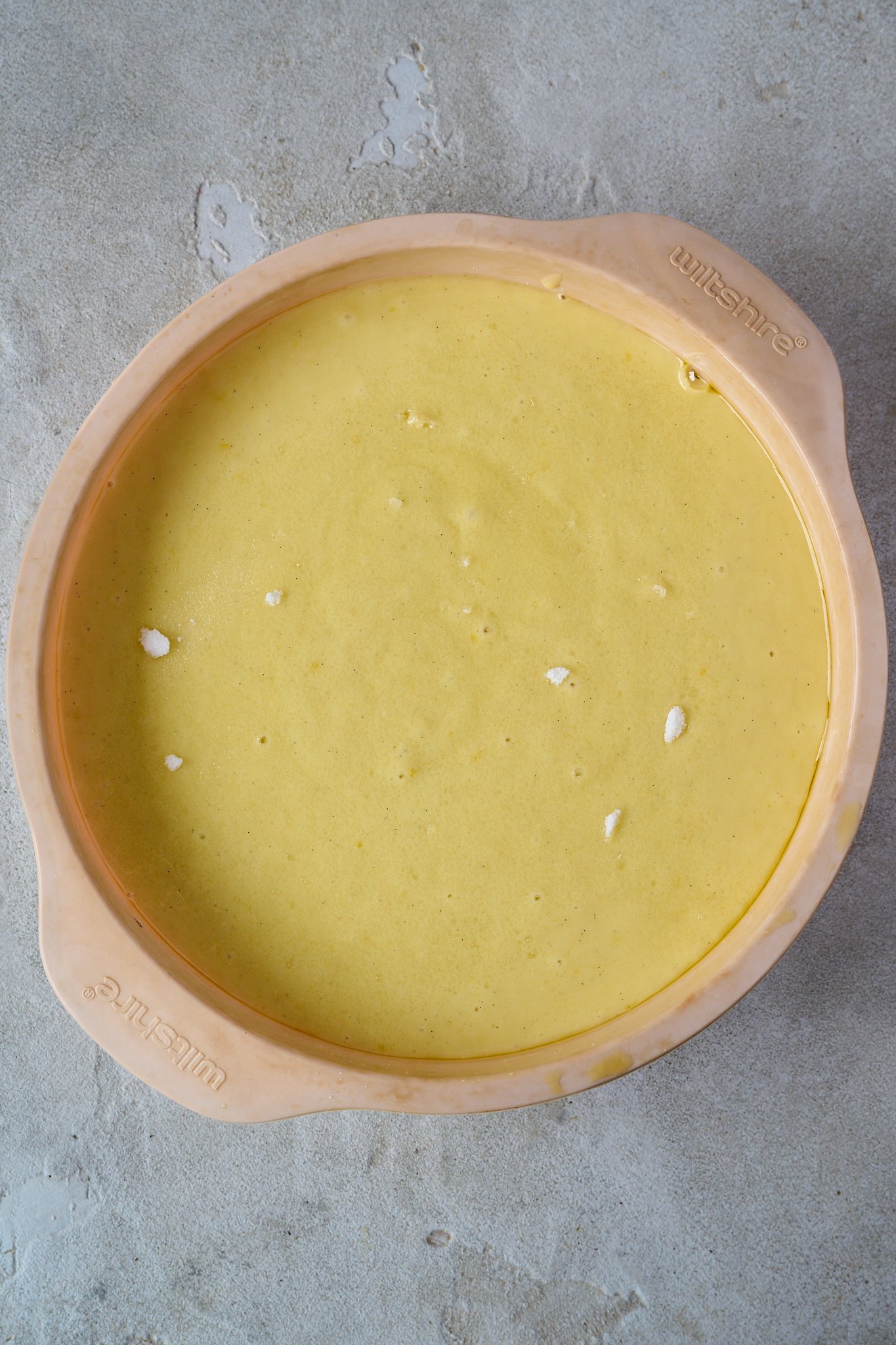 batter for lemon olive oil cake is in pink silicone cake tin