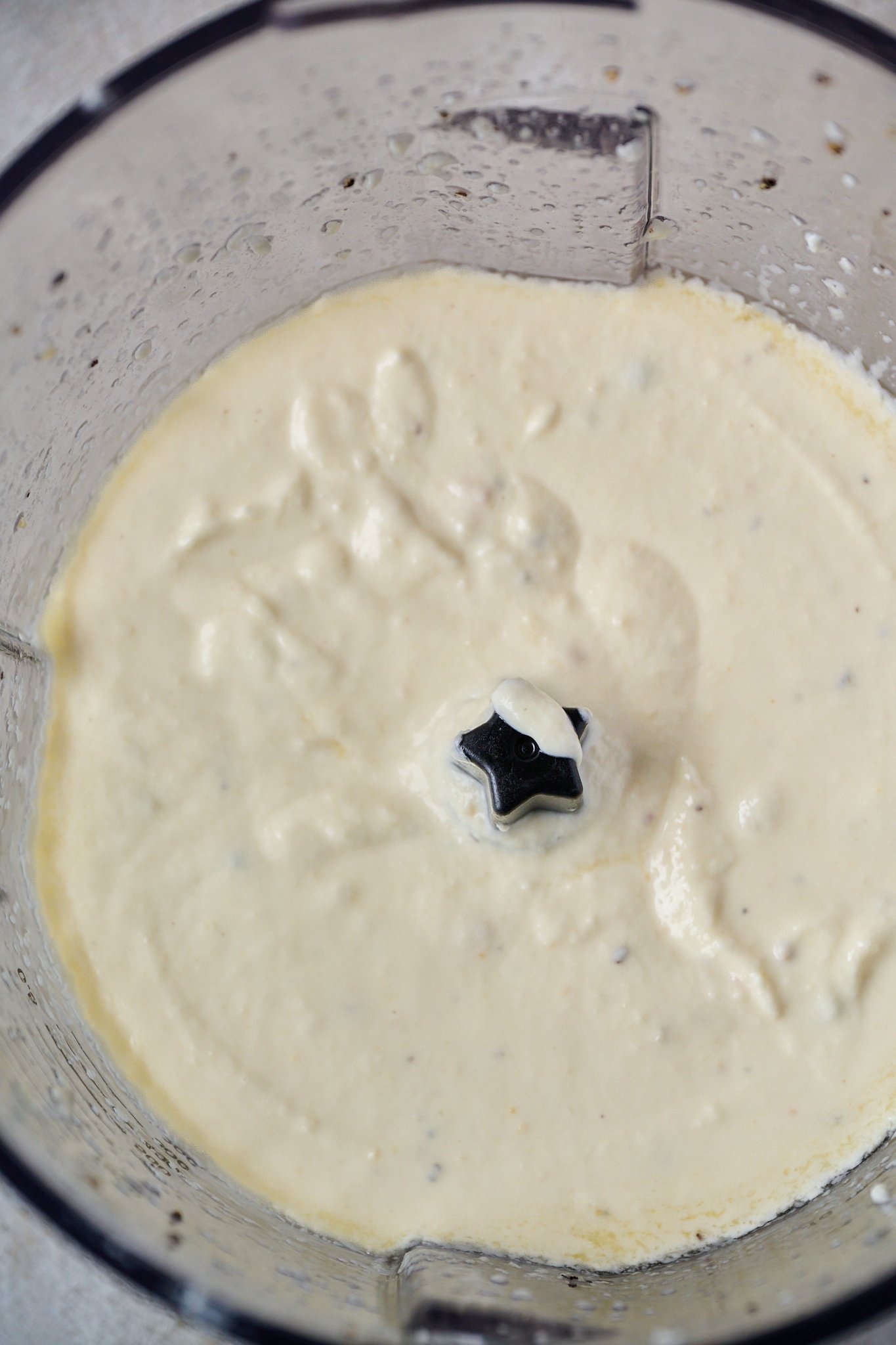 A food processor is shown with whipped goat cheese inside. 