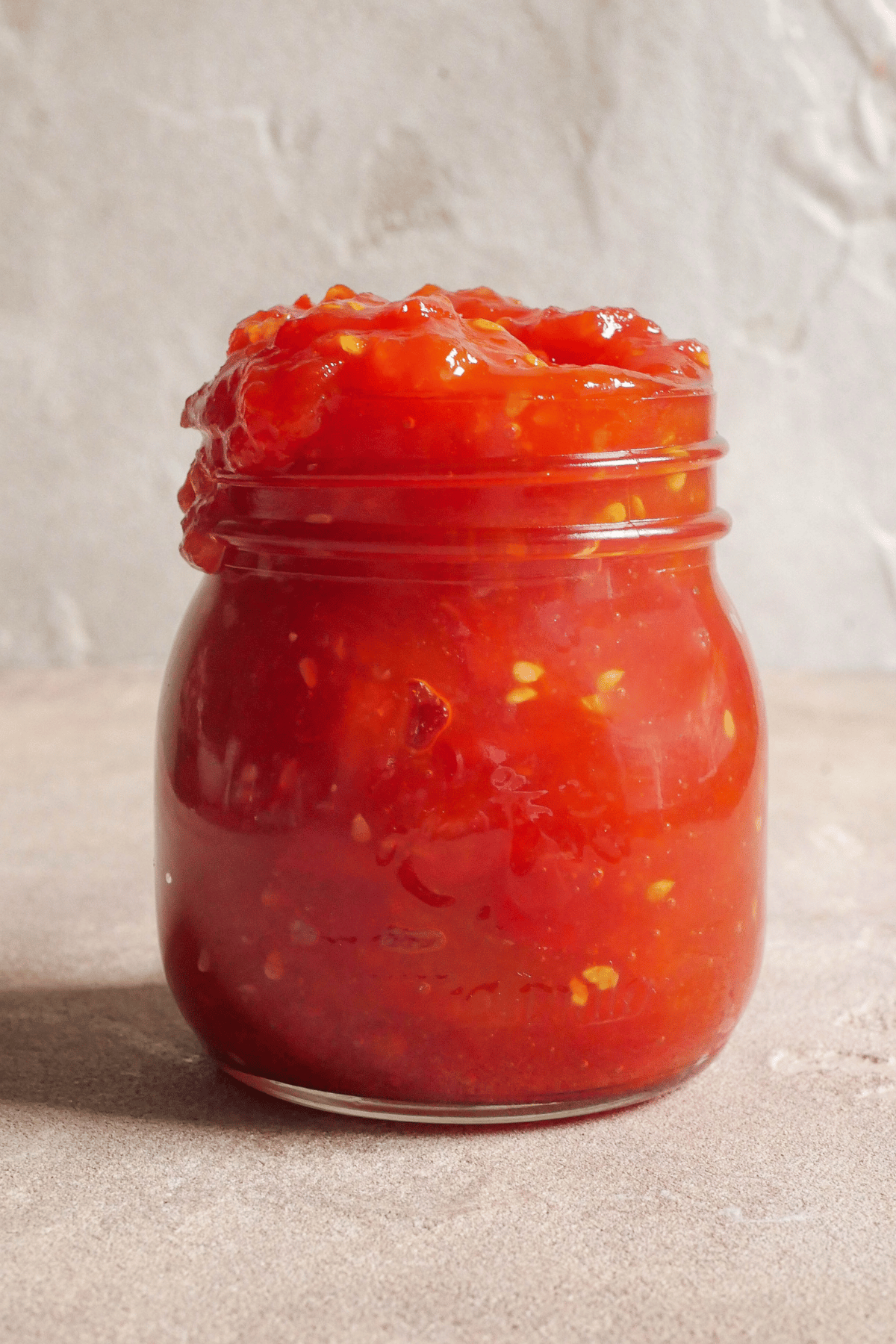 Close up image of glass jar with tomato jam in it.