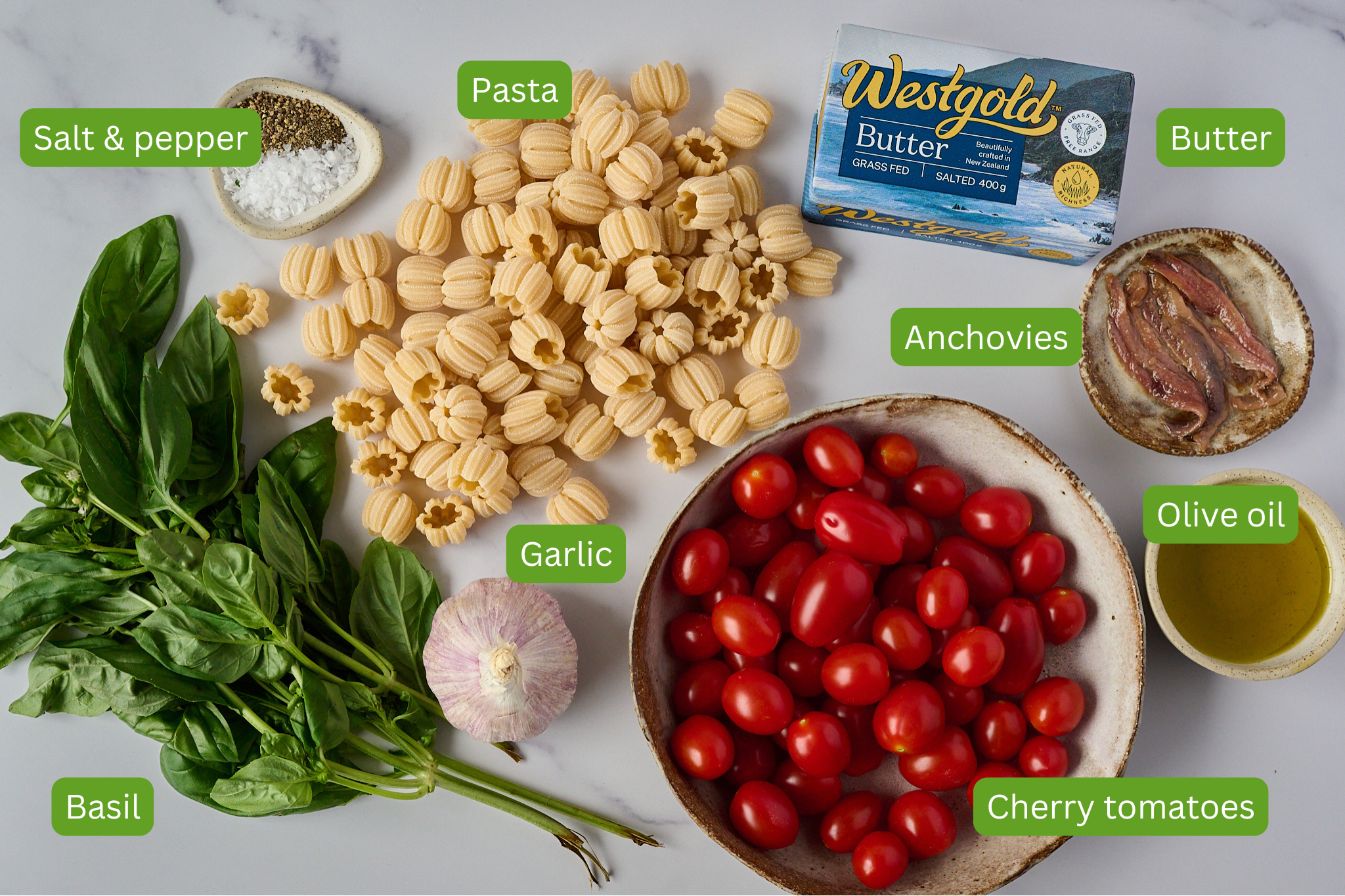 Ingredients for tomato and butter pasta are shown including pasta, salt and pepper, Butter, anchovies, basil, cherry tomatoes, olive oil and garlic. 