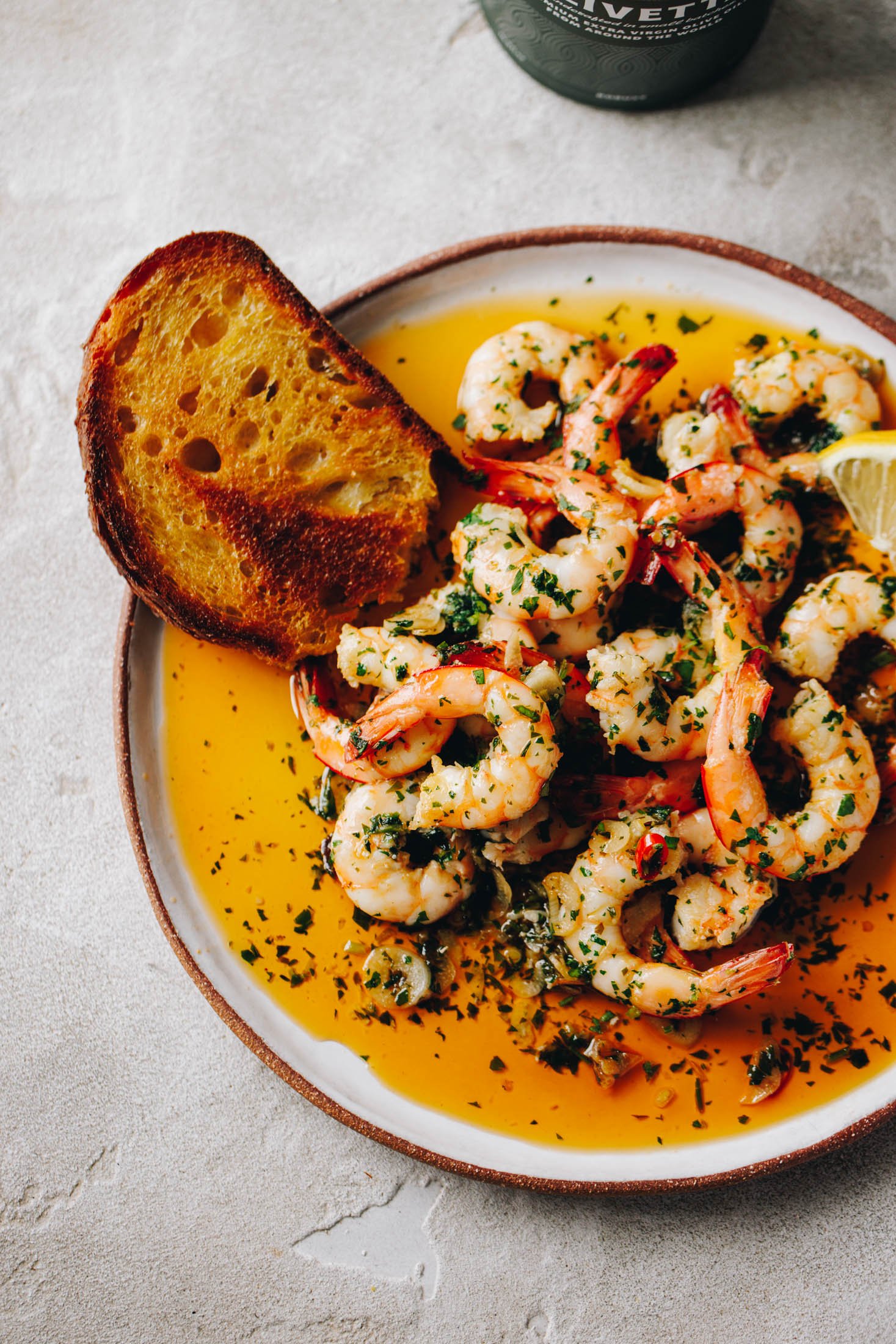 Spanish Garlic Shrimp (Prawns) - Gambas al Ajillo sit in plate with crusty piece of bread sitting out the side. 