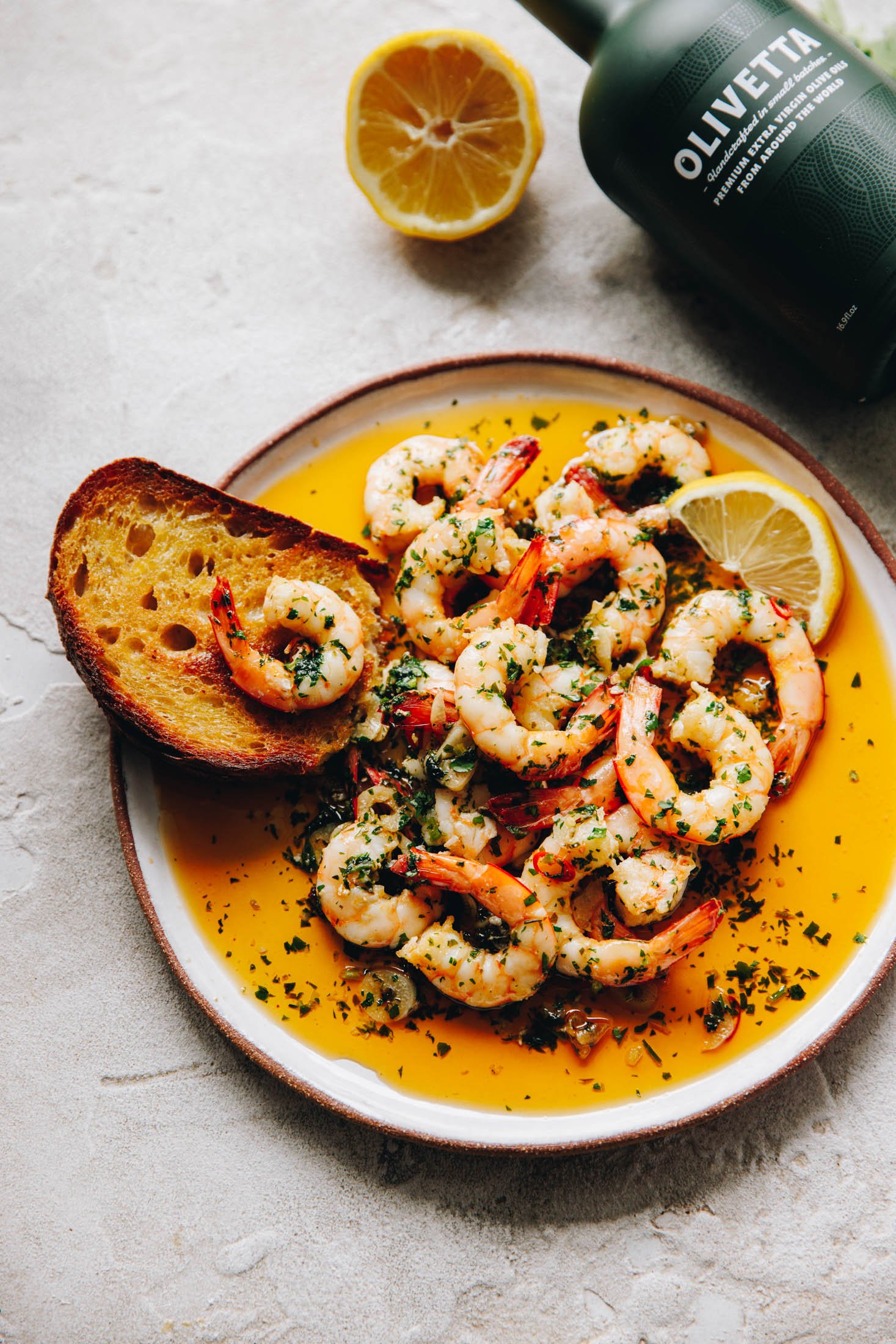 Spanish Garlic Shrimp (Prawns) - Gambas al Ajillo sit in plate with crusty piece of bread sitting out the side. 