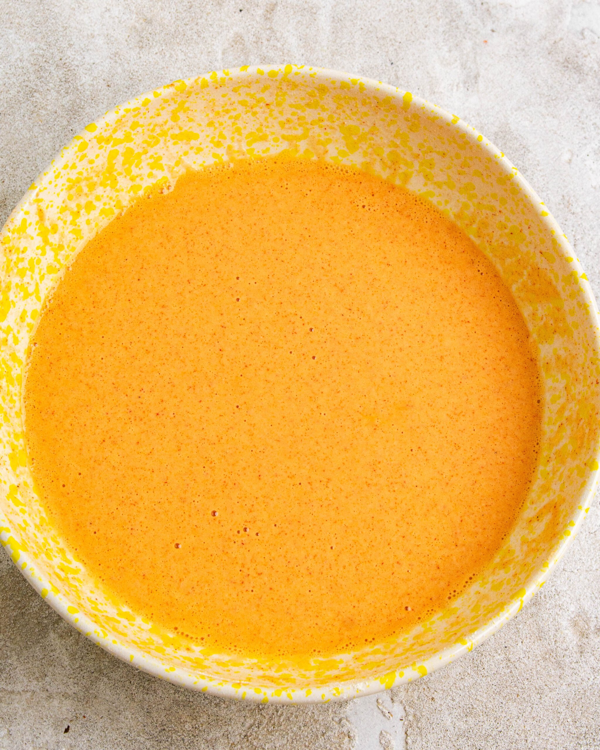 Beer batter has been prepared and sits in yellow bowl. 